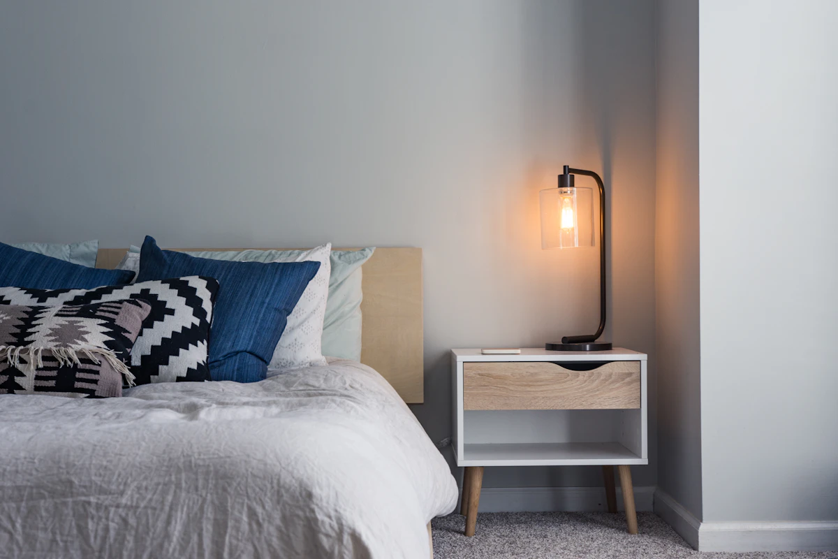 Slaapkamer met een bed, nachtkastje en lamp